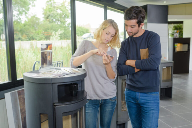 Un couple devant un poêle à bois avec une calculatrice en main